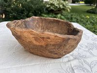 Side view of the natural olive wood bowl showing rounded shape, wood grain and texture.