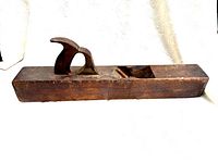 Side view of the primitive wooden hand planer showing the handle and the opening for the blade.