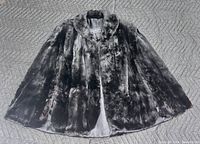 Full view of the black and brown fur cape laid flat showing the rounded collar and the overall fur texture and color variation.