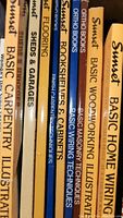 Spine view of several hardcover instructional books on carpentry, masonry, wiring, and woodworking, to identify titles and authors