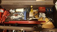 Open toolbox top compartment showing assorted tools including microphone, pliers, adjustable wrench, flashlight, cords, and small boxes with components.