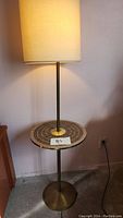 Full view of floor lamp with off-white cylindrical shade and integrated round mosaic tile side table