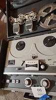 Sony Stereocorder reel to reel tape recorder with two wired microphones, control knobs, and reels visible, placed inside open carrying case.