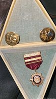 Two US brass military pins together with Speed Accuracy award medal in a triangle box with hinged lid.