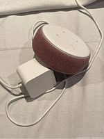 Amazon Echo Dot 3rd Generation smart speaker showing red fabric body and white adapter with cable.