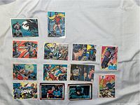 Photo showing all 12 Batman 1966 Topps trading cards laid out on a fabric background, featuring a variety of action and character scenes, some with visible corner wear.