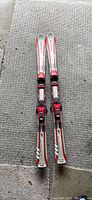 Top view of the pair of Elan skis showing the red, white, and silver color scheme with Marker bindings attached.