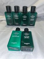 Six Hermes Eau D’orange Verte bottles arranged in two rows, showing front and top labels, identifying shampoo, conditioner, and body lotion.