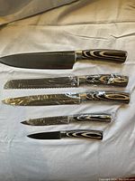 All five knives laid flat, blades visible, handles showing laminated wood pattern
