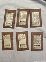 Six sealed Le Labo fragrance sample envelopes laid flat showing front labels with fragrance names and barcodes.