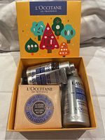 Box containing L'Occitane en Provence bath gift set with colorful tree design on lid and four product items inside.