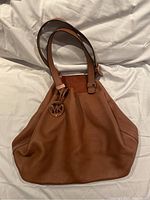 Full view of brown leather purse with two shoulder straps and rounded shape.