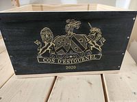 Front close-up of wine crate black panel showing gold crest logo and text 'COS D'ESTOURNEL 2020'