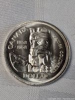Front side of the 1958 Canada silver dollar coin showing the totem pole and inscriptions