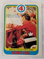 Front of the 1978-79 Bobby Orr Special Collectors Card showing Bobby Orr in hockey uniform on bench surrounded by blue and yellow border with red stars and number 4.