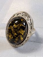 Close-up front view of sterling silver ring with oval amber stone showing golden inclusions and detailed silver setting.