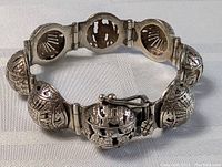 Front and detail view of sterling silver bracelet with altered angles showing motifs on linked globes and clasp mechanism
