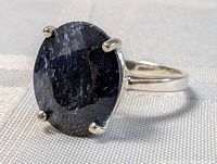 Close-up of large oval faceted sapphire set in sterling silver ring band.