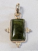 Front view of the sterling silver pendant with rectangular dark green stone and decorative silver bead accents.