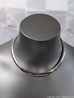Front view of sterling silver thick collar necklace displayed on a mannequin to highlight the necklace's shape and thickness.