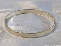 Full view of the sterling silver bangle bracelet showing the carved geometric motif on the exterior surface.