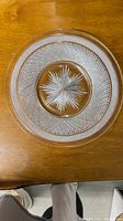 Top-down view of one clear cut crystal plate showing starburst center and diamond-cut textured design on rim.