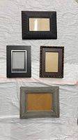 Photo showing four assorted picture frames laid out on a light surface.