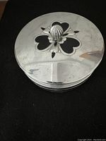Closed view of chrome lid with decorative finial and heart-shaped cutout designs