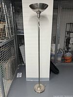 Full view of the tall chrome standing lamp showing its round base, slim pole, and bowl-shaped top shade.