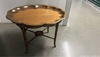 Full view of oval scalloped wood coffee table showing top and legs.