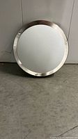 Front view of round flush mount ceiling light with silver metal trim and white frosted glass diffuser.