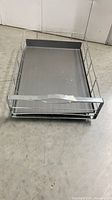 simplehuman chrome pull-out cabinet organizer placed on floor showing front view and wire frame construction.