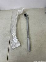 Full length view of the 18 inch ratcheting breaker bar including its packaging plastic sleeve.