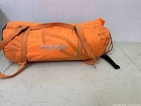 Orange Flytop tent carry bag lying on flat surface showing overall condition and strap.