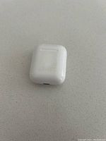 Closed white charging case for Apple AirPods, showing wear with scuff marks on surface.