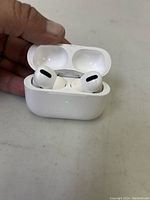 Open charging case showing both AirPods Pro earbuds inside with green LED indicator light on