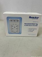 Front and top view of the box showing the product image and key features like six outlets, three USB ports, surge protection, and smart USB.