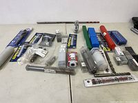 Wide view of drill bits and accessories spread on table, showing various brands and packaging