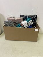 Cardboard box containing various household items including bags, kitchen organizers, and bedding items.