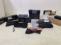 Full view of sunglasses, blue light glasses, pouches, and boxes arranged on flat surface.