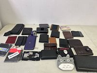 Entire lot of wallets and pouches arranged on a table, showing variety of styles and colors.