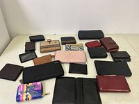 Overview of 18 wallets and pouches laid out on a white surface in various sizes and colors.