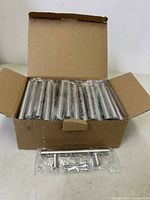 Open cardboard box showing 30 individually wrapped silver cabinet handles.