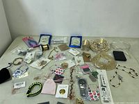 Wide view of assorted costume jewelry pieces and jewelry making supplies laid out on a surface.