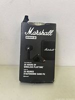 Front of the product box showing Marshall Minor 3 branding and product features including 25 hours wireless playtime and Bluetooth support. Box top is damaged.