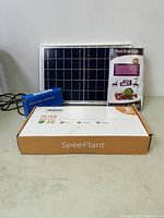 Photo showing solar panel, blue solar charge controller, and boxed SpeePlant T5 LED grow light
