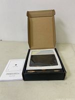 Open box showing Timemore Black Mirror Basic 2 coffee scale in protective foam packaging with instruction manual visible.