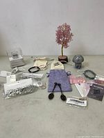 Wide view of assorted women's lot items including bracelets, earrings, necklaces, crystal spoons, decorative crystals, and collectibles arranged on a table.