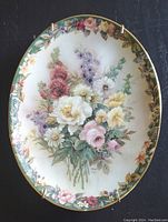 Front view of the oval plate showing floral painting and gold trim.