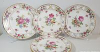 Set of six side plates shown front view on stands, displaying floral patterns and gold trim